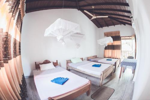 a room with two beds and a table and chairs at Rupa's Hotel in Arugam Bay