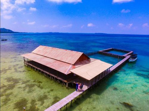 a dock in the ocean with a boat in the water at New Cottage Asri Karimunjawa in Karimunjawa
