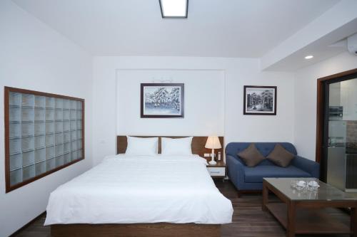 a bedroom with a white bed and a blue couch at Cat Linh ARL55 Hotel in Hanoi