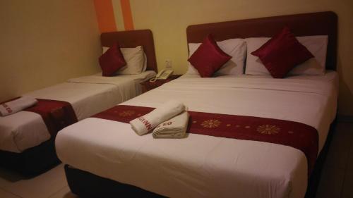 two beds in a hotel room with red pillows at Sun Inns Hotel Equine, Seri Kembangan in Seri Kembangan