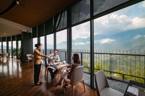a group of people sitting at a table in a room with windows at Pao's Sapa Leisure Hotel in Sa Pa