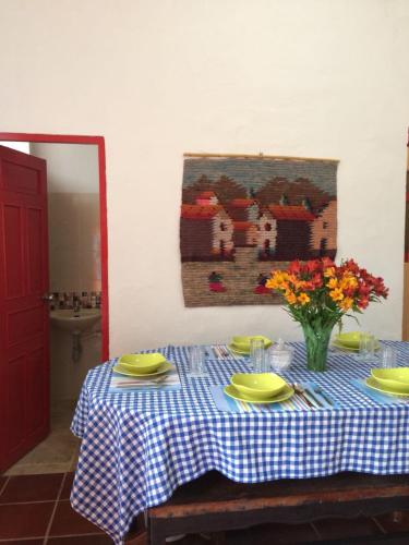 a table with yellow plates and a vase of flowers on it at Posada Turistica Nakku in Silvia