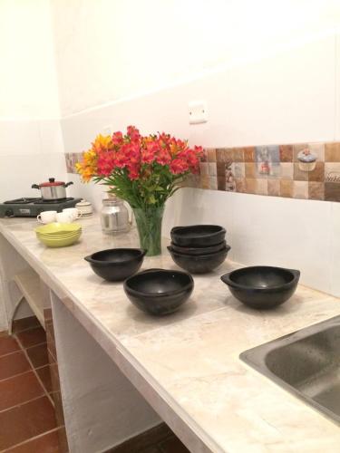a kitchen counter with four bowls and a vase of flowers at Posada Turistica Nakku in Silvia