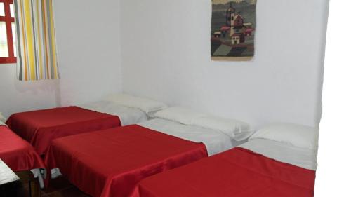a room with three beds with red sheets at Posada Turistica Nakku in Silvia