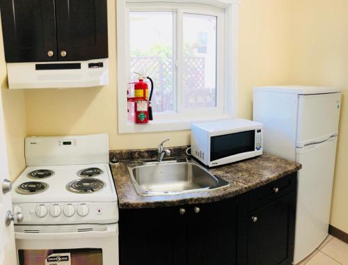 a kitchen with a sink and a stove and a microwave at Kings Motor Inn in Kamloops