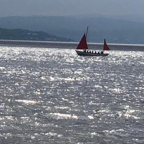 a boat with a red sail in the water at Brookwood Sea View 14 in Dunoon