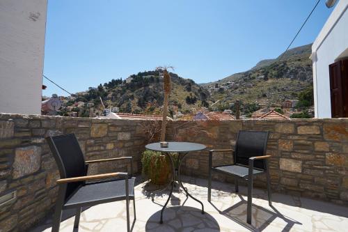 a patio with three chairs and a table on a wall at Kaminos Boutique Hotel in Symi