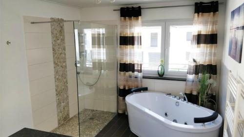 FeWo - bei Tati 95qm في سينجين: حمام مع حوض استحمام ودش زجاجي
