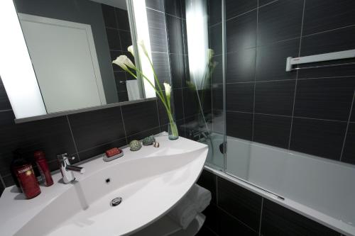 a bathroom with a sink and a mirror and a tub at Aparthotel Adagio Vienna City in Vienna