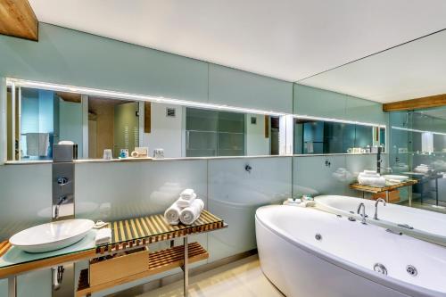 a bathroom with a tub and a sink and mirrors at The Henry Jones Art Hotel in Hobart