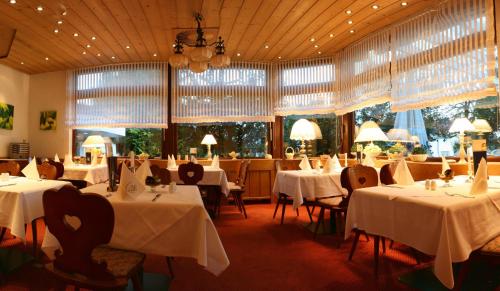 a restaurant with white tables and chairs and windows at Landhotel Sonnenbühl in Sonnenbühl