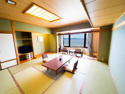 a room with a table and chairs and a view of the ocean at Naruto Grand Hotel Kaigetsu in Naruto