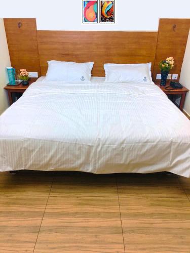 a large bed with white sheets and two night stands at Shivalaya hotel in Pudukkottai
