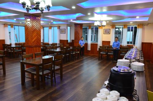 two people standing in a restaurant with tables and chairs at Hotel Golden Sunrise & Spa in Pelling