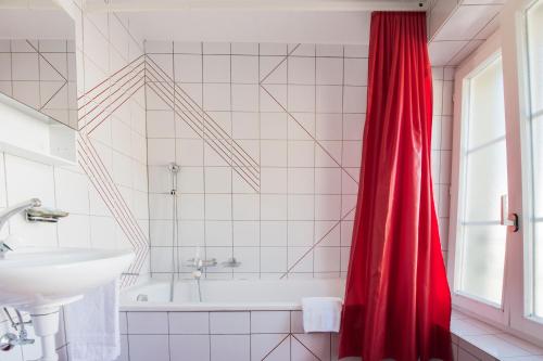 bagno con tenda doccia rossa e lavandino di Hôtel-de-Ville d'Attalens a Attalens