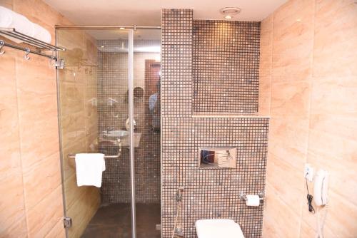 a bathroom with a glass shower with a sink at Celesta - Kolkata in Kolkata