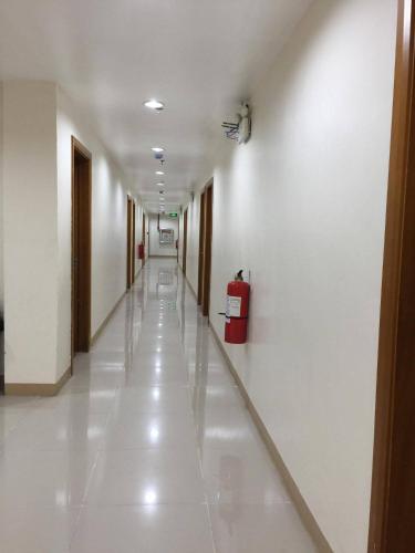 a long hallway with white walls and a red suitcase at Meaco Royal Hotel - Lipa in Lipa