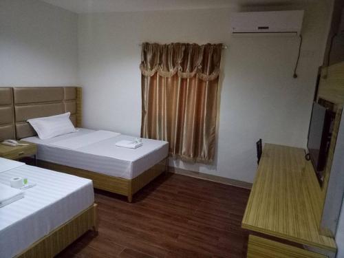 a hotel room with two beds and a window at Meaco Royal Hotel - Tabaco in Tabaco