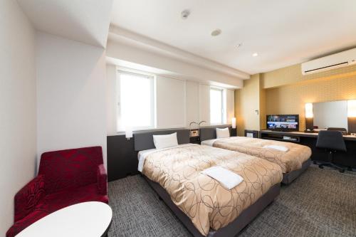 una camera d'albergo con letto, scrivania e TV di Sanco Inn Shizuoka Kitaguchi a Shizuoka