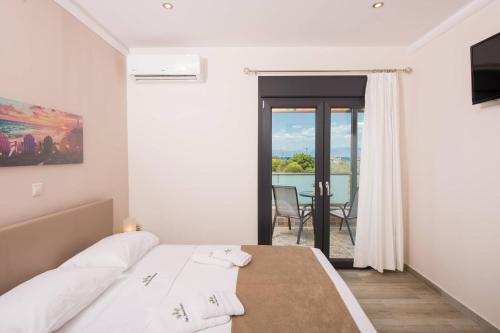 a white bedroom with a bed and a balcony at Ftery in Skala Rachoniou