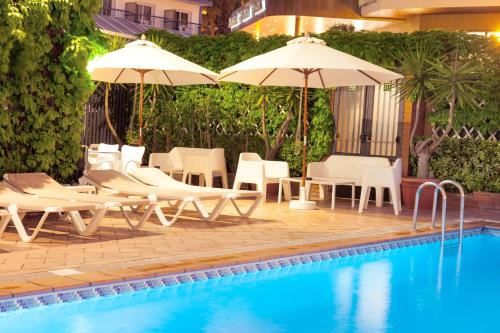 uma piscina com cadeiras e guarda-sóis ao lado de uma piscina em Hotel Xaine Park em Lloret de Mar