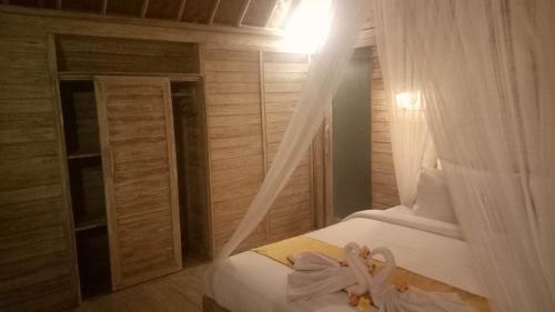 a bedroom with a bed with a white curtain at Tiki bar and more in Nusa Lembongan