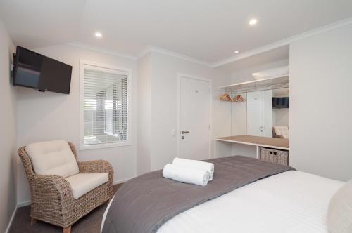 a bedroom with a bed and a chair and a television at Luxury Rata Apartment - A in Twizel
