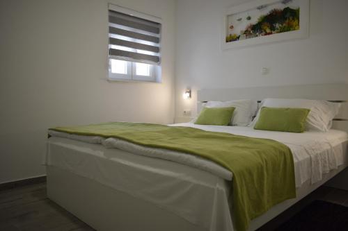 a bedroom with a large bed with a green blanket on it at Bozikovic 365 in Podstrana
