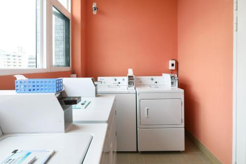 uma lavandaria com máquinas de lavar roupa brancas e uma parede laranja em MINI HOTELS (Taichung Station Branch) em Taichung