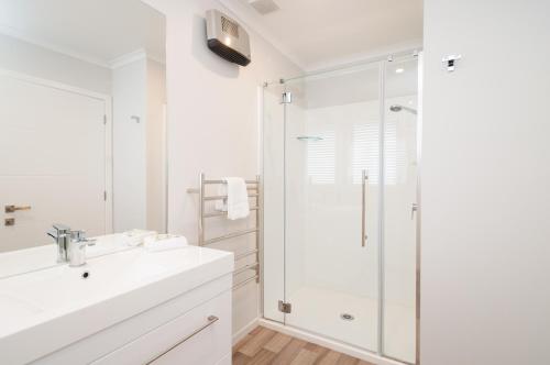 uma casa de banho branca com um chuveiro e um lavatório. em Luxury Rata Apartment - B em Twizel