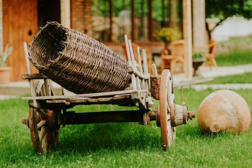 a wicker cart sitting in the grass in a yard at Hotel & Wine Cellar ARGE in Tʼelavi
