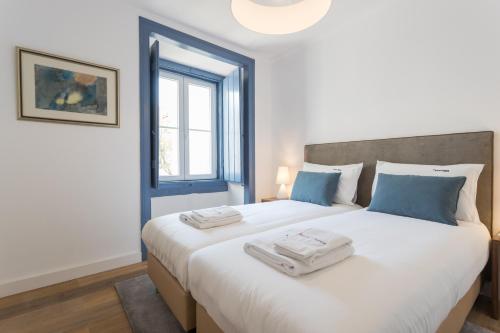 リスボンにあるFLH Mouros Comfortable Placeのベッドルーム1室(大きな白いベッド1台、タオル2枚付)