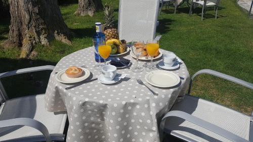 een tafel met een wit tafelkleed met stippen en drankjes bij Hostal Restaurante Carolina in Pedrosillo el Ralo