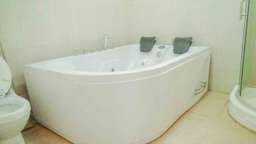a white bath tub in a bathroom with a toilet at Avon Garden Lodge in Salima
