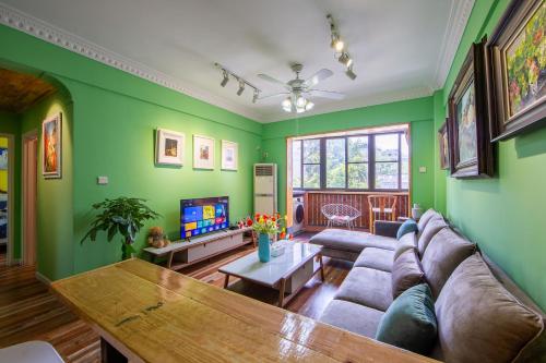 a living room with green walls and a couch and a table at Guangzhou He She Art Apartment in Guangzhou
