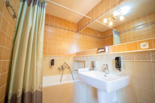 a bathroom with a sink and a bath tub at Hotel Tivoli in Vysoké Tatry