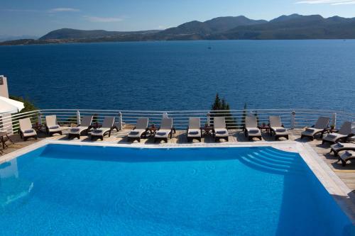 uma piscina com cadeiras e vista para a água em Adriatica Hotel em Nikiana