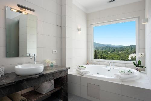 a bathroom with a tub and a sink and a window at Gem Villa in Viros Corfu in Virós