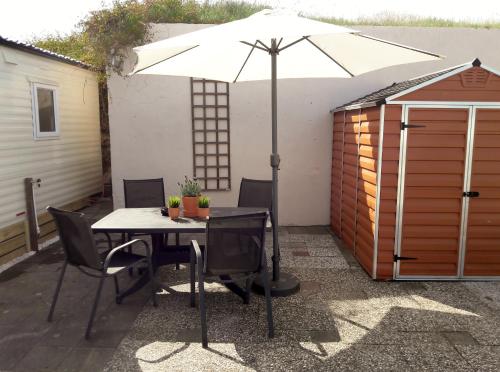 a table and chairs with an umbrella on a patio at Chalet Dalile IJmuiden aan Zee vlakbij het strand in IJmuiden