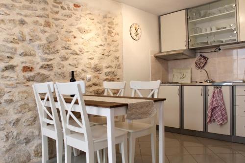 a kitchen with a wooden table and white chairs at Lavanda in Tribunj