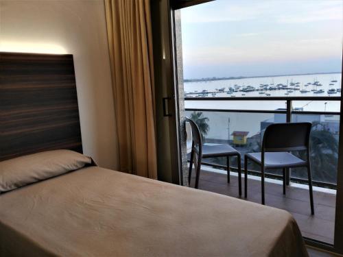 a bedroom with a bed and a balcony with a view at Hotel Ribera in Santiago de la Ribera