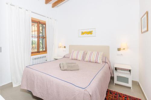 a white bedroom with a bed and a window at Cas Garriguer in Andratx