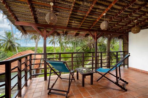 a porch with two chairs and a table on it at Seven Turtles in Tangalle