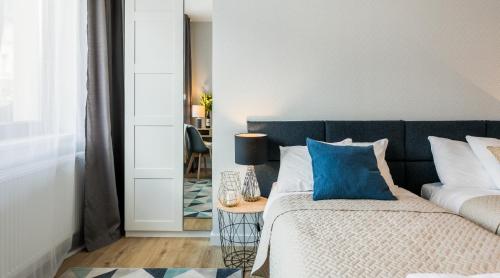 a bedroom with a bed with blue pillows and a table at Vistula Boutique Exclusive Apartments in Krakow