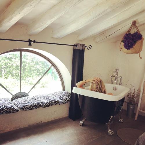 a woman in a bath tub in a room with a window at Cabana del Tio Pepe in Ainzón