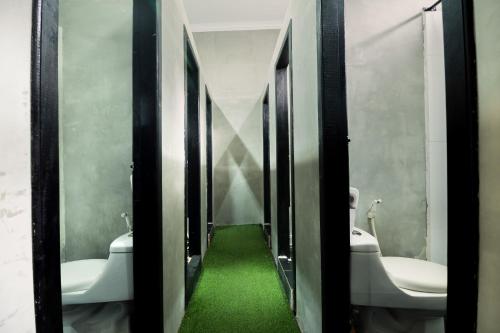 uma casa de banho com dois WC e um piso verde em Pool Party Hostel em Siem Reap