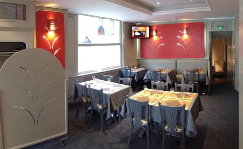 a restaurant with tables and chairs in a room at Hôtel Les Frangins in Saint-Omer