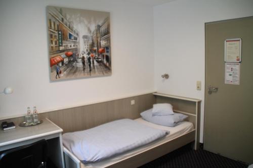 a small room with a bed and a painting on the wall at Autobahn Motel Siegerland Ost in Siegen