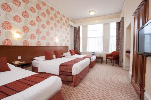 a hotel room with four beds and a flat screen tv at TLH Toorak Hotel - TLH Leisure, Entertainment and Spa Resort in Torquay