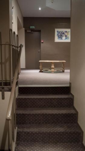 a hallway with stairs and a bench in a building at Hôtel Les Frangins in Saint-Omer